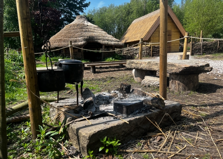 Picture shows a campfire, and in the background a roundhouse and longhouse.